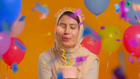 Studioporträt-Einer-Frau-Mit-Hijab-Und-Geburtstagskönigin-Stirnband,-Die-Ihren-Geburtstag-Feiert-Und-Kerzen-Auf-Dem-Kuchen-Ausbläst